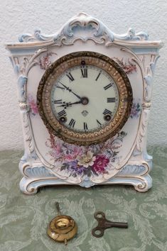 an ornate clock with flowers on it next to a pair of scissors and a key