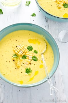 two bowls of soup with corn on the cob and parsley garnish