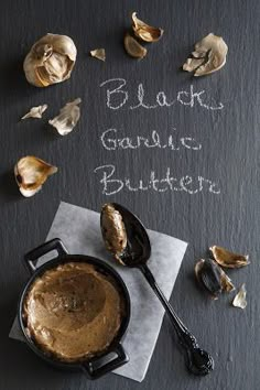 black garlic butter in a cast iron skillet with spoons next to it on a slate board