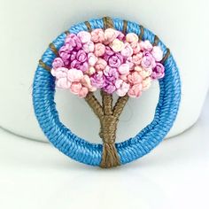 a small tree made out of yarn sitting on top of a toilet bowl cover holder