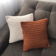 two crocheted pillows sitting on top of a couch