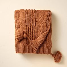 a brown knitted blanket with tassels on it and a pom - pom