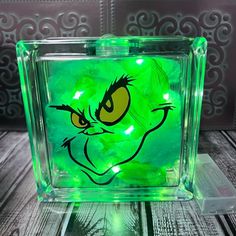 the grin face glows green in this square glass block with an acrylic design