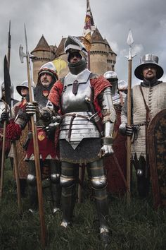 men dressed in medieval armor standing next to each other with swords and shields on their hands