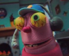 a close up of a cartoon character wearing a baseball cap and eye patch with two balls in his mouth