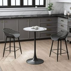 two chairs and a table in a kitchen with marble counter tops, gray cabinets and white walls