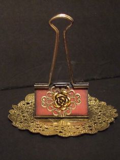 a red and gold purse sitting on top of a doily with a metal handle