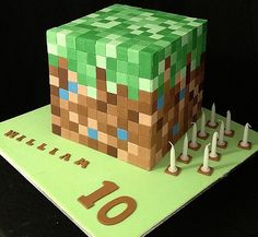 a cake made to look like a minecraft block with candles on it and the number 10