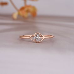 a rose gold ring with a diamond in the middle on a table next to flowers