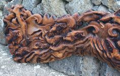 a carved piece of wood sitting on top of a stone wall next to a pile of rocks