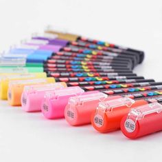 several different colored ink pens lined up on a white surface with the same color as each one