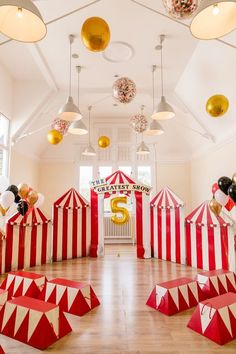 a room filled with lots of red and white striped tents next to balloons in the air