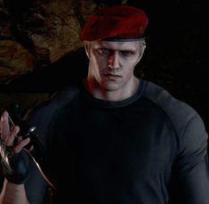 a man in a black shirt and red hat holding a cell phone next to a cave