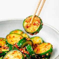 a white bowl filled with sliced cucumbers and topped with sesame seeds