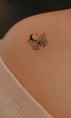 a small butterfly tattoo on the back of a woman's shoulder