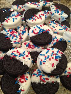 oreo cookies with white frosting and sprinkles are on a glass platter