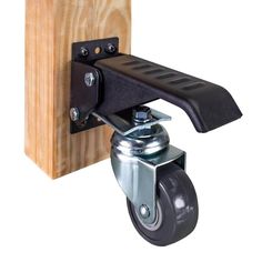 a black casteor with a wooden block on the back and one wheel attached to it