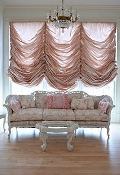 a living room filled with furniture and a chandelier hanging from the ceiling next to a window