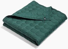 a green blanket folded up on top of a white surface with a buttoned closure