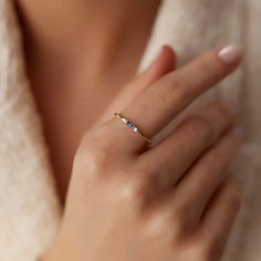 a woman wearing a gold ring with blue stones