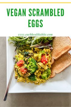 a white plate topped with scrambled eggs and veggies next to a slice of bread