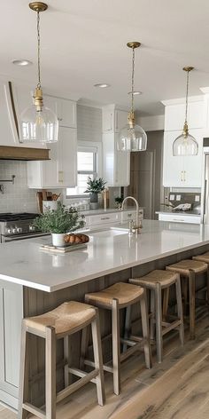 a large kitchen island with stools next to it and lights hanging from the ceiling