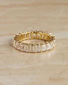 a gold ring with baguettes on it sitting on top of a wooden table