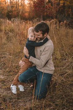 a father holding his son in the middle of a field during an autumn photo session