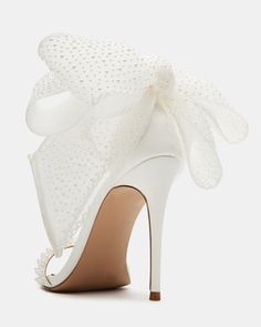 a white shoe with a large bow on the side and heels that are covered in pearls