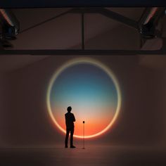 a man standing in front of a painting with an orange and blue circle behind him