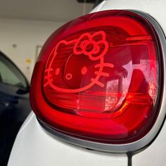 a hello kitty sticker is on the back of a white car in a garage