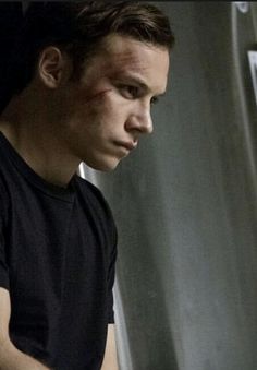 a man in black shirt sitting next to a refrigerator