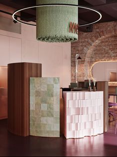 the interior of a modern restaurant with brick walls and green lighting fixture hanging from the ceiling