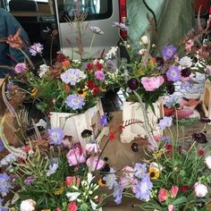 several vases filled with colorful flowers on top of a wooden table next to a truck