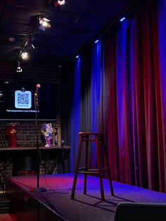 the stage is set up for an event with red and blue curtains, stools, and lights