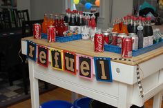 there is a table with sodas and cans on it that says refreshment