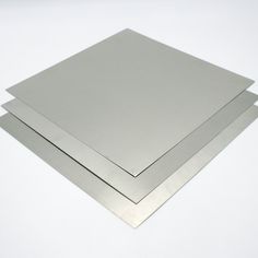 two pieces of metal sitting next to each other on a white surface with one piece missing