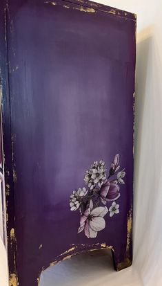 a purple painted cabinet with flowers on it