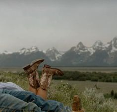 a person laying on the ground with their feet up in the air and wearing cowboy boots