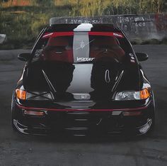 the back end of a black sports car parked in a parking lot with graffiti on it