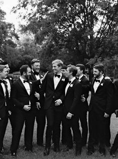 a group of men in tuxedos standing next to each other on the grass