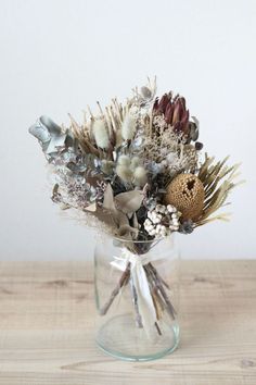 a vase filled with dried flowers on top of a wooden table