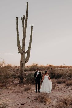 a bride and groom standing in front of a saguado