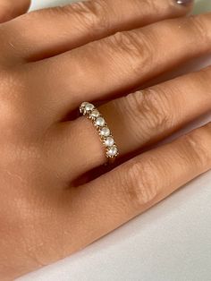 a woman's hand with a ring on it and pearls in the middle of her finger