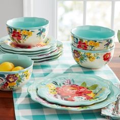 a table topped with plates and bowls covered in flowers on top of a checkered table cloth