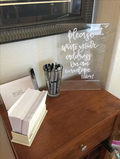 a clear acrylic sign sitting on top of a wooden desk next to a pen holder