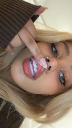 a woman with long blonde hair and piercings on her nose is making a silly face