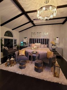 a bedroom with a large bed and chandelier hanging from the ceiling