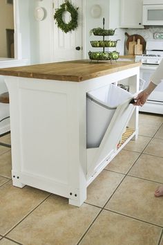 a kitchen island with a trash can in it and a person standing next to it