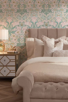 a large bed sitting in a bedroom next to a wallpaper covered with pink and green flowers